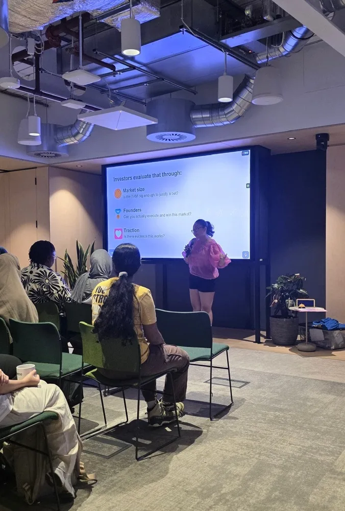 Rebecca presenting a slide to a seated audience in a workspace