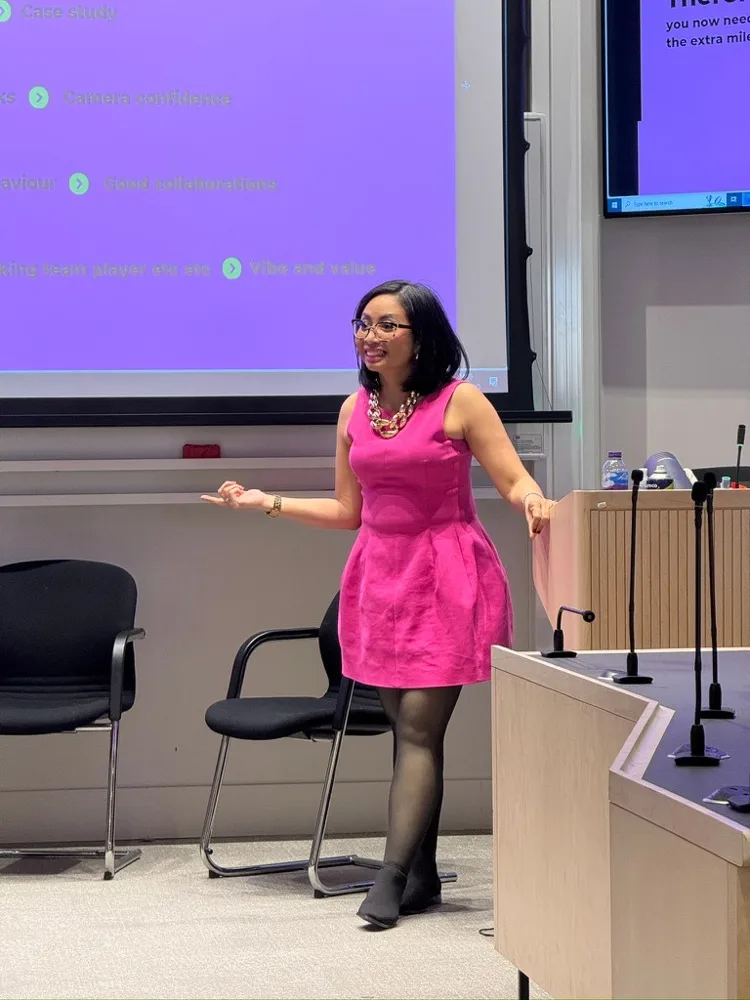 Rebecca in a pink dress presenting beside a lectern