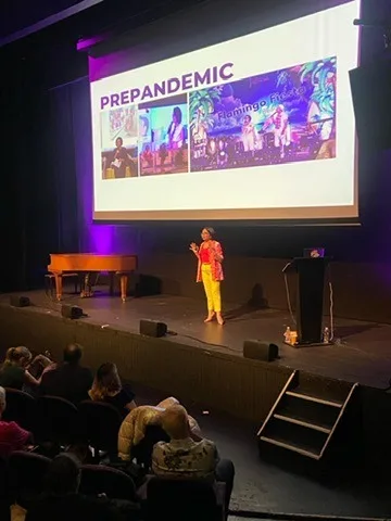 Rebecca on a theatre stage beneath a Prepandemic slide