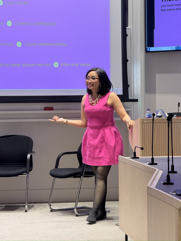 Rebecca Leppard presenting in a pink dress in front of a presentation screen