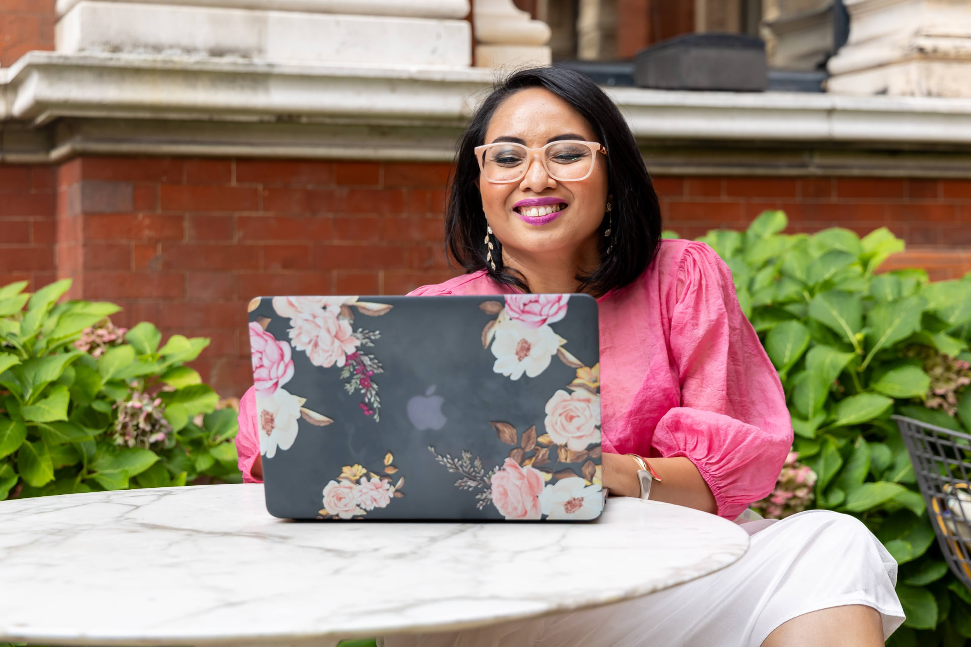 Rebecca Leppard in a pink blouse working at a laptop with a floral cover