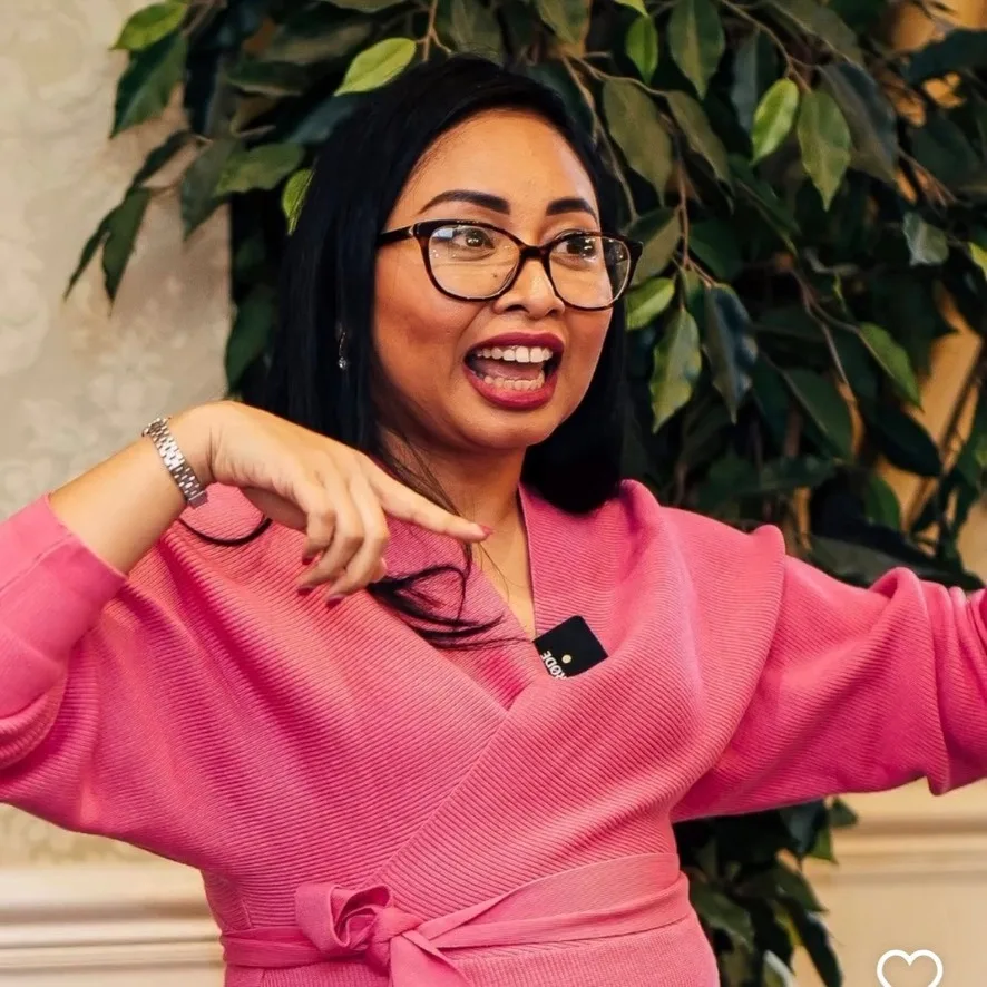 Close-up of Rebecca in pink gesturing as she speaks