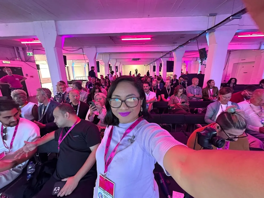 Rebecca taking a selfie in front of a large event audience