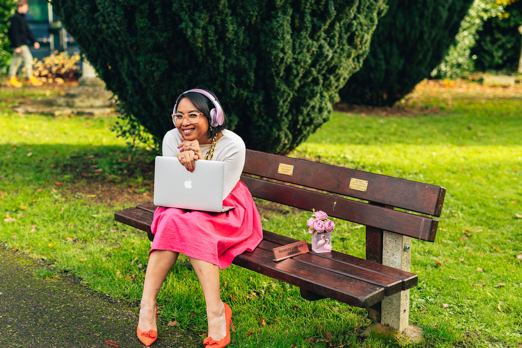 Rebecca Leppard sitting on a park bench with her laptop